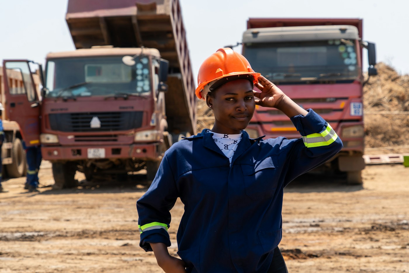Site engineer in a hard hat in front of delivery trucks