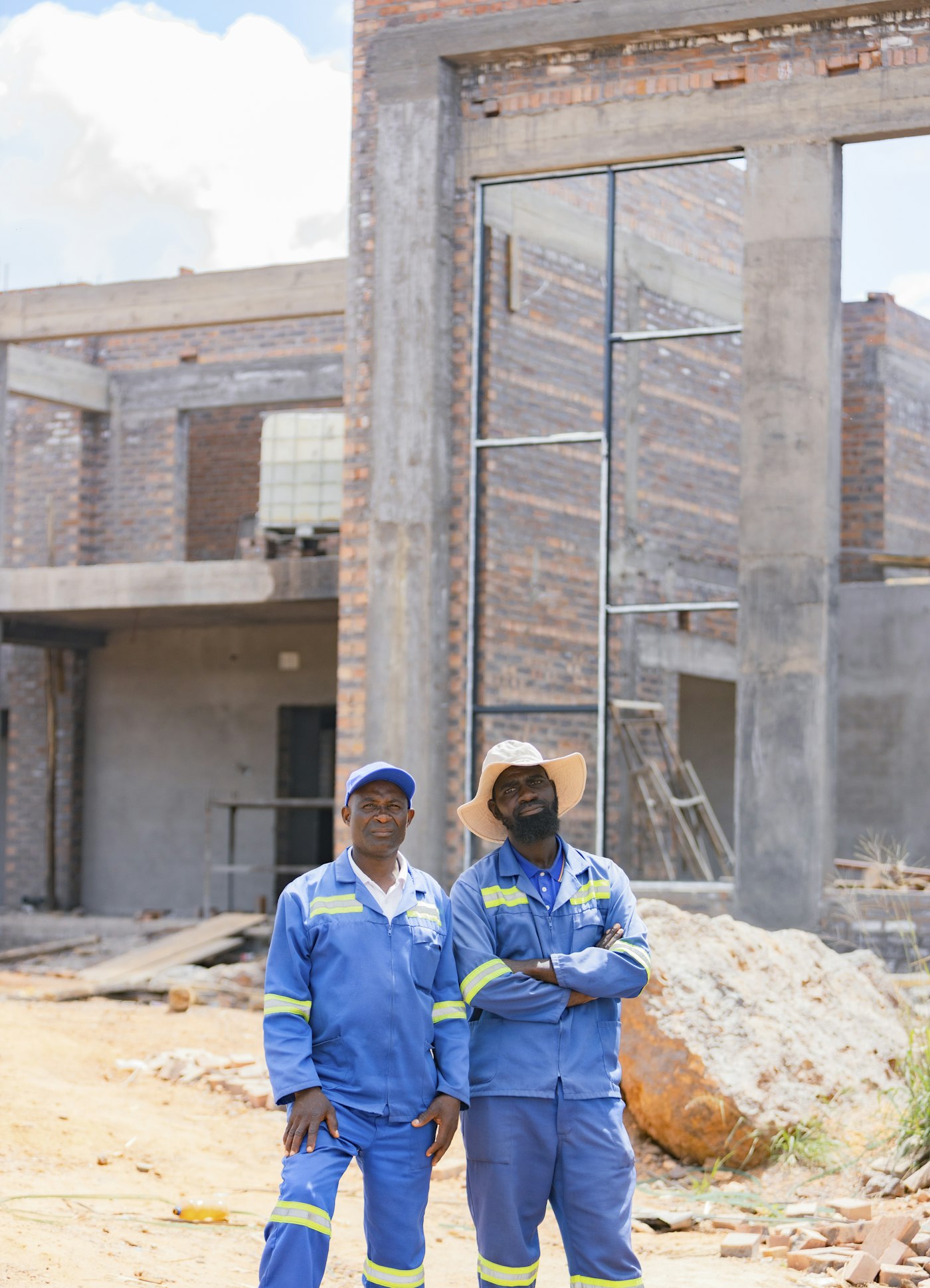 Two site supervisors in work uniforms in front of a building under construction