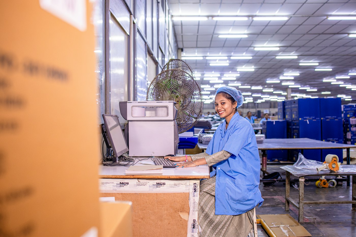 Warehouse clerk in a blue uniform working at a computer in a distribution warehouse