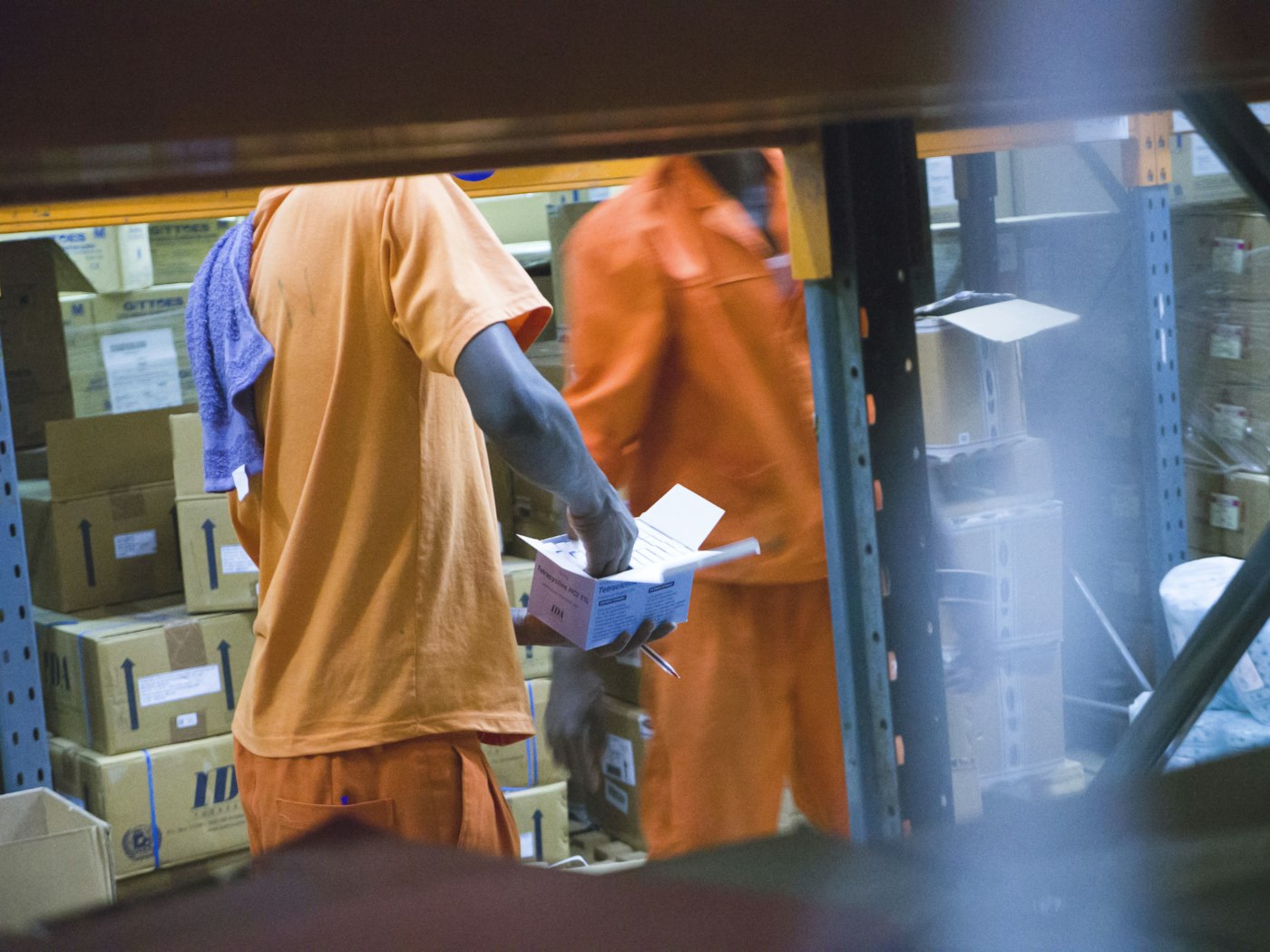 Warehouse workers in orange picking boxes from shelves