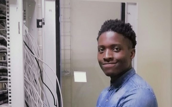 Network technician smiling beside a server rack