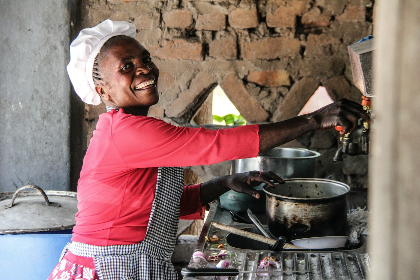 Cook in a red shirt smiling at the stove