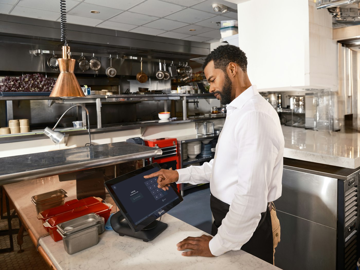 Waiter entering an order on a touch screen in a restaurant kitchen