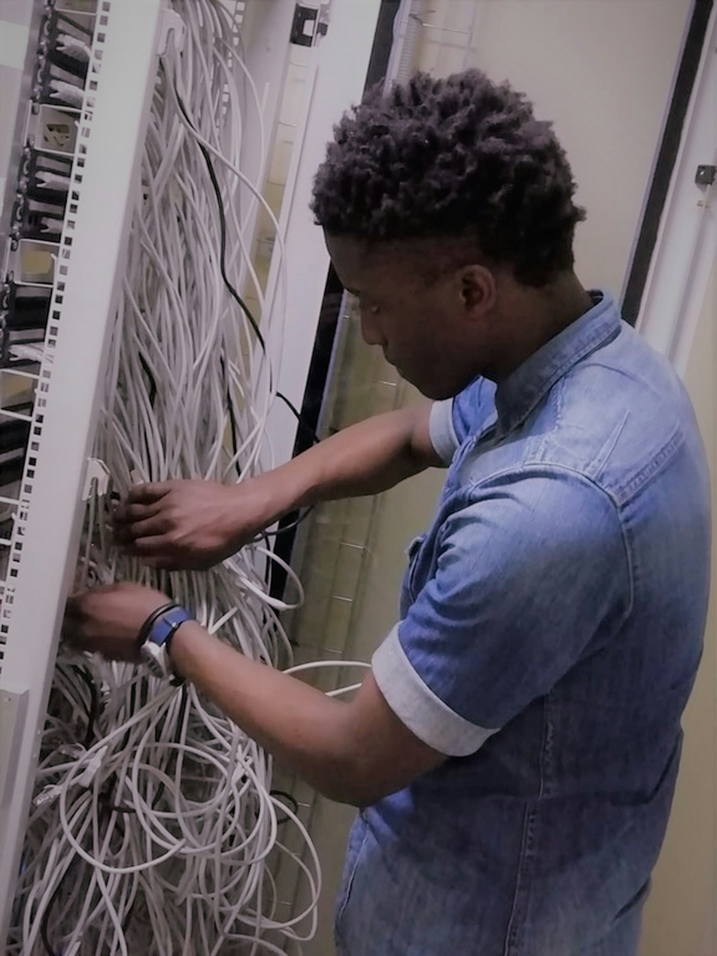 Network technician in a denim shirt working at a fibre cabinet