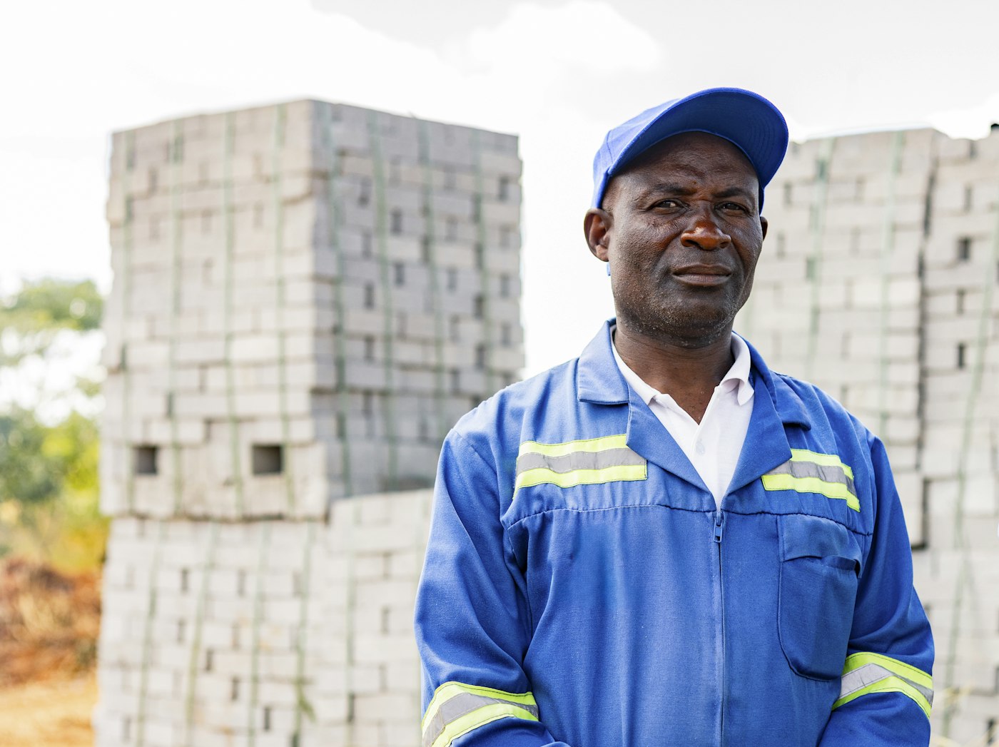 Factory supervisor in blue work overalls in front of stacked building blocks