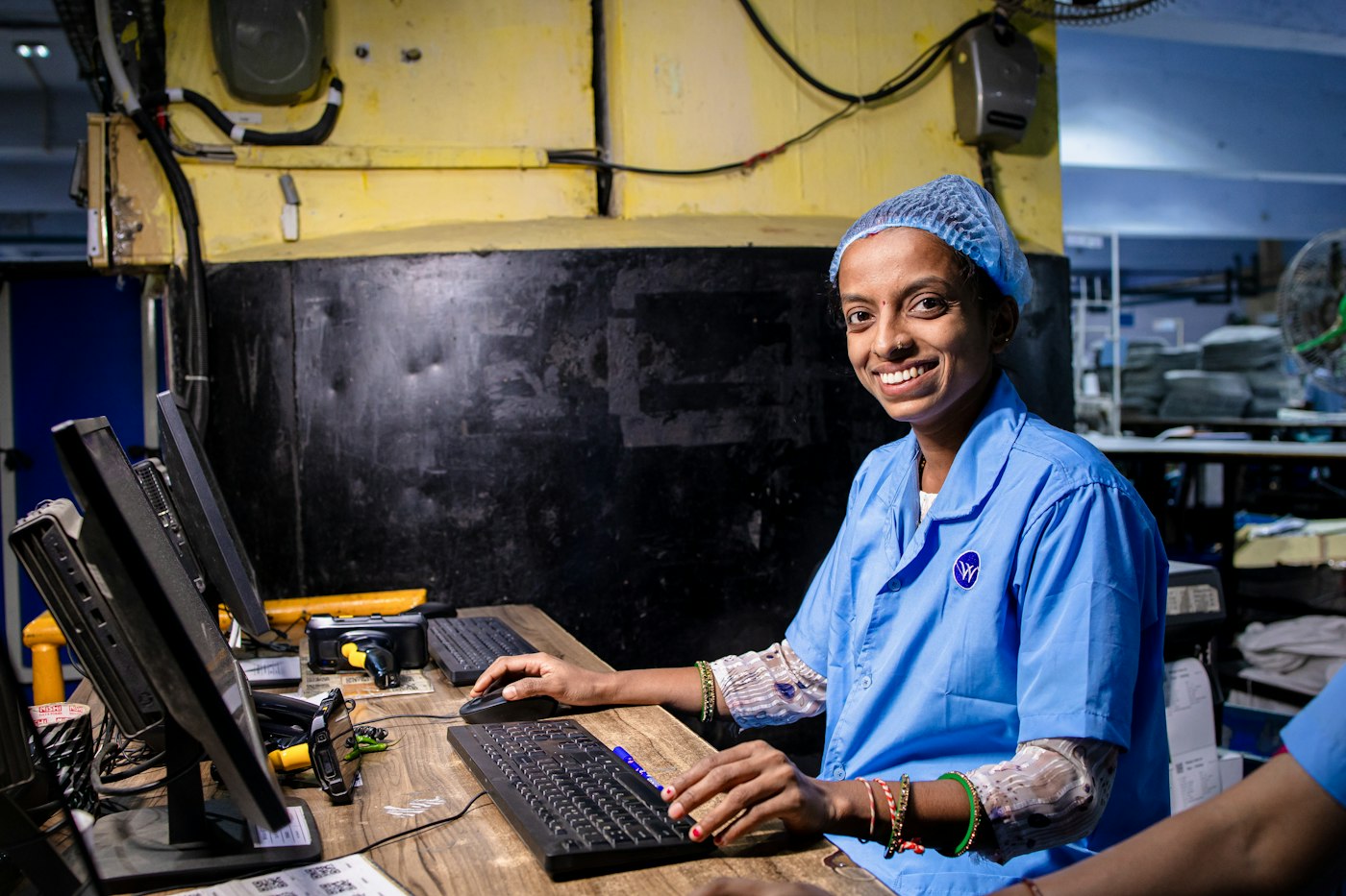 Factory technician in uniform working at a computer on the shop floor