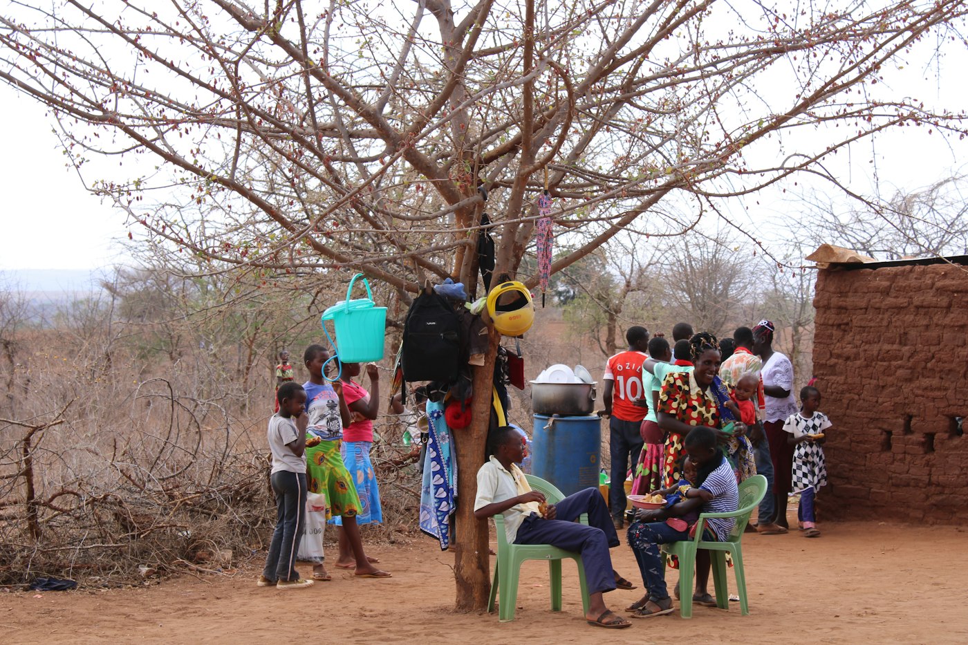 Community members gathered under a tree for an outreach meeting