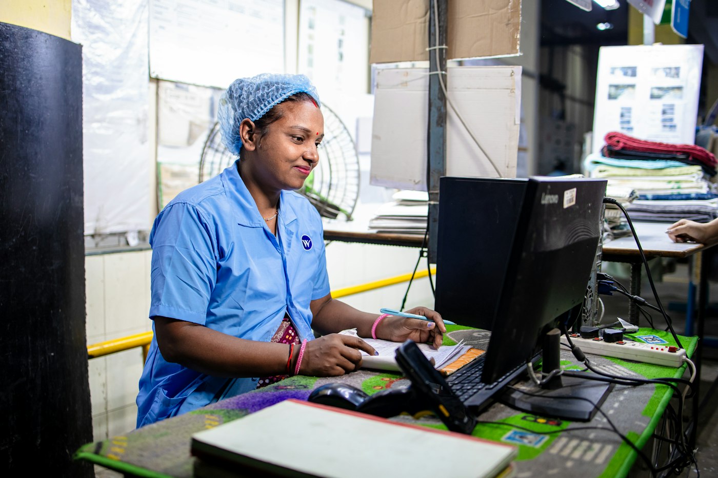Programme officer in a blue uniform working at a computer