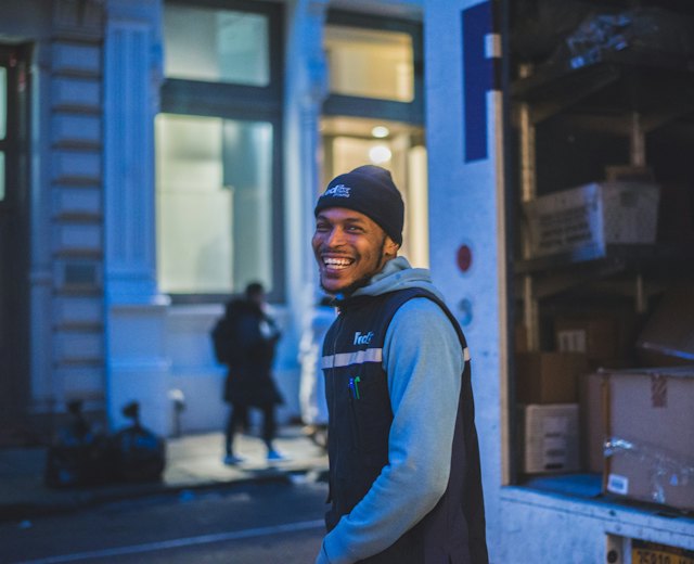 Delivery driver smiling beside his van