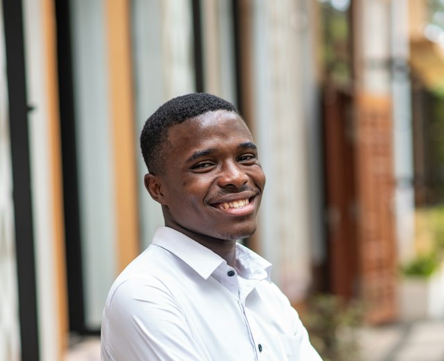 Branch manager in a white shirt smiling outside his shop