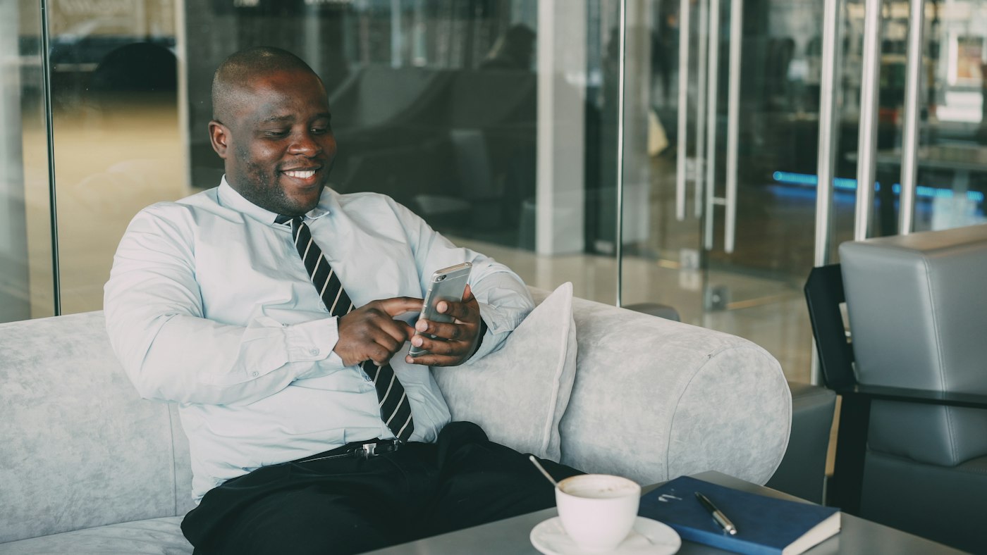 Partner smiling at his phone in the office lounge