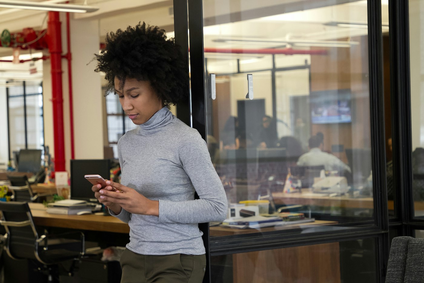 Business owner checking approvals on her phone in the office