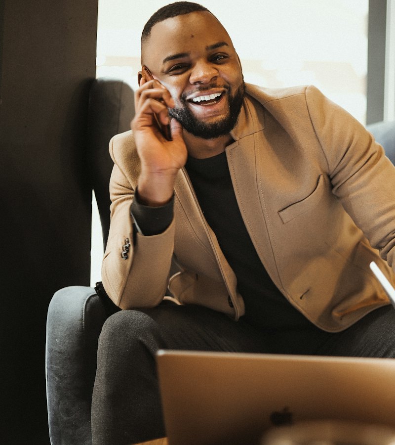Business owner laughing on a phone call at his laptop