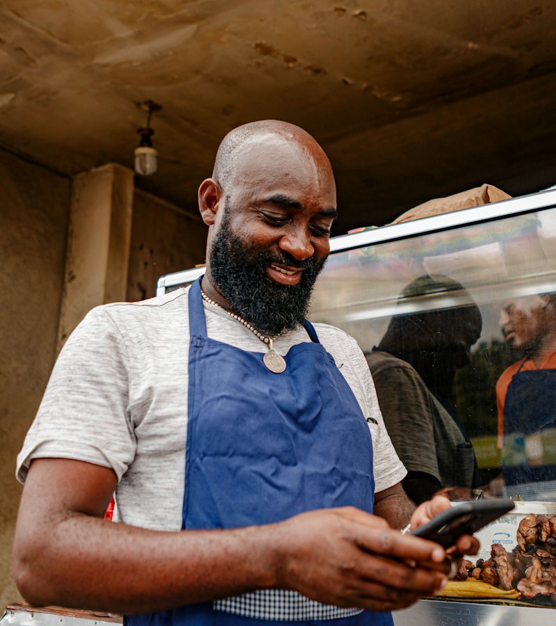 Food vendor smiling as he checks a customer payment on his phone